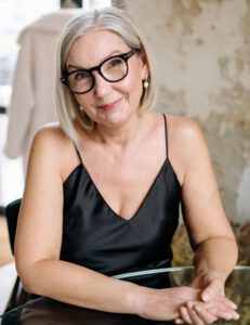 Elegant senior woman with glasses smiling indoors. Refined and graceful ambiance.